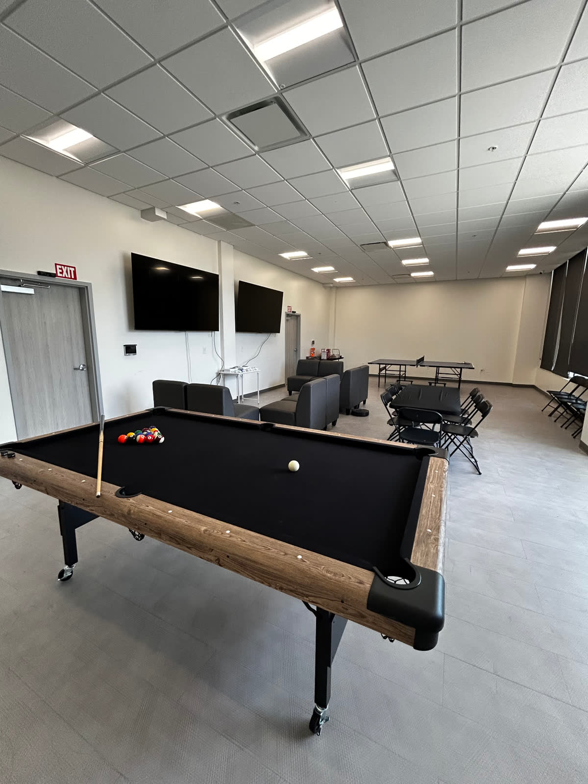Inside the Teen Lounge — pool table, lounge seating, ping pong table, and dual TVs in the members-only clubhouse at The Link