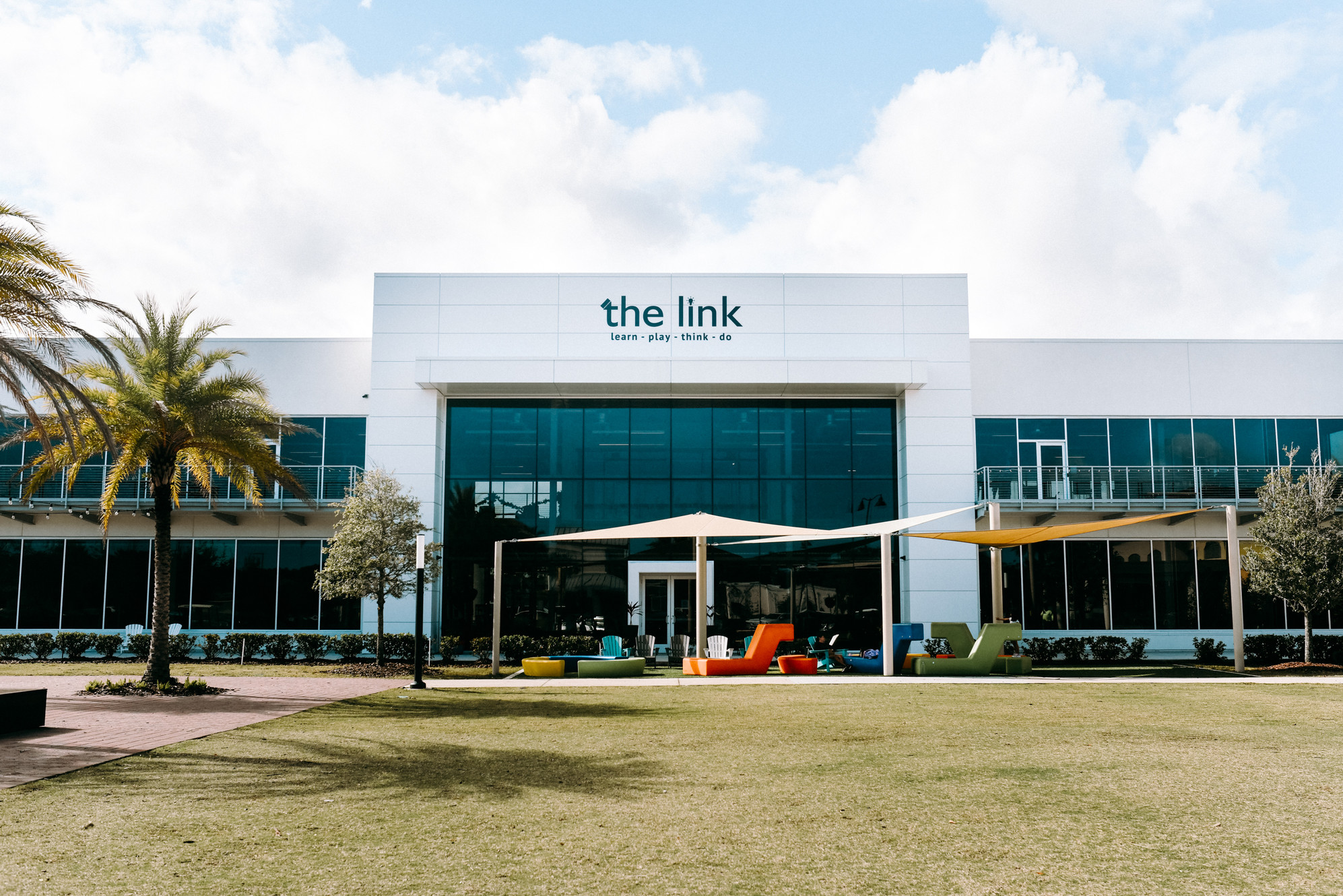 Exterior of The Link innovation center in Nocatee, Florida — a modern glass and stone building at 425 Town Plaza Avenue that houses the Teen Lounge